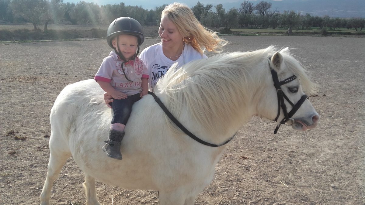 Nia giving her daughter her first horse-riding lesson on her pony Lilly